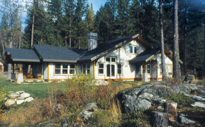 
A view of the home’s south side shows the use of stone-colored stucco finish, slate-colored roofing, and natural wood trim accents, which all tie the house to its location.
